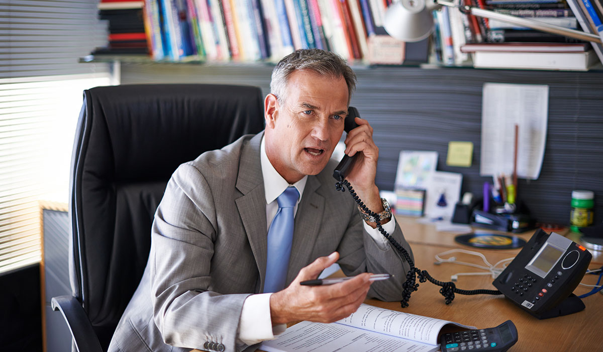 Business owner reacts with surprise during a phone call about enquiries from potential company buyers.